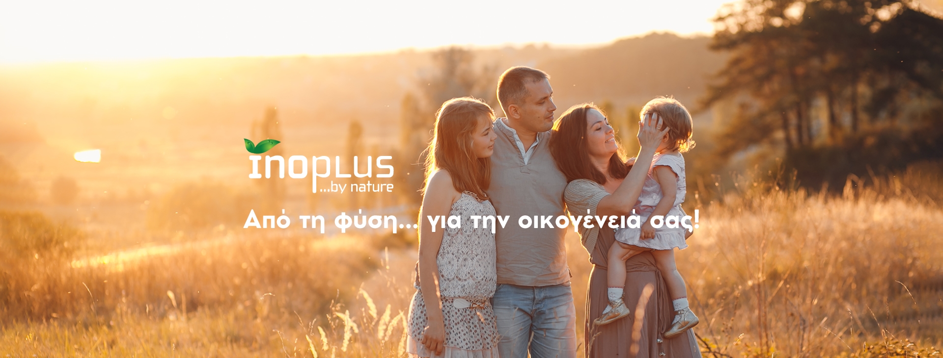 Μια τετραμελής οικογένεια βρίσκεται σε ένα χωράφι στο sunset, με το κείμενο "inoplus" και "Από τη φύση... για την οικογένεια σας!" στα ελληνικά. Εμφανίζεται στο Banner Inoplus.