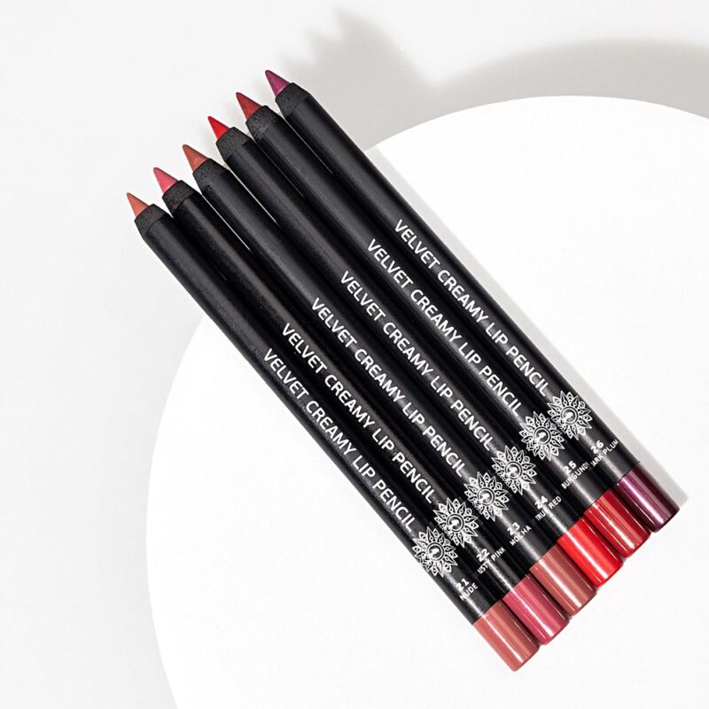 Garden-Velvet-Lip-Pencils Επτά Garden-Velvet-Lip-Pencils σε διάφορες αποχρώσεις στηρίζονται κομψά σε μια παρθένα λευκή κυκλική επιφάνεια.