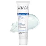 Ένα σωληνάριο Uriage Bariederm Cica Creme με μια γαλάζια κρέμα από πίσω του.