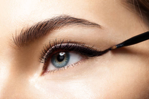 Κοντινό πλάνο κάποιου που χρησιμοποιεί το Eyeliner για να εφαρμόσει μαύρο λάινερ στο πάνω βλέφαρό του με ένα πινέλο.