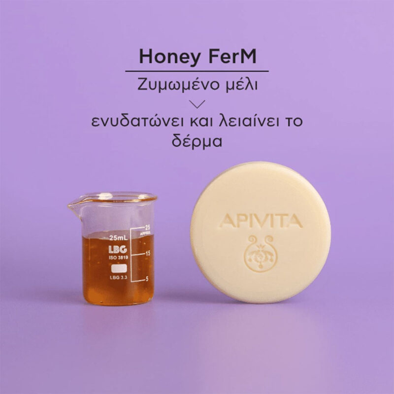 Ένα ποτήρι με μέλι και ένα Apivita Solid Foamy Cleanser Face & Eyes 80g βρίσκονται σε μοβ φόντο, με ελληνικό κείμενο από πάνω τους.